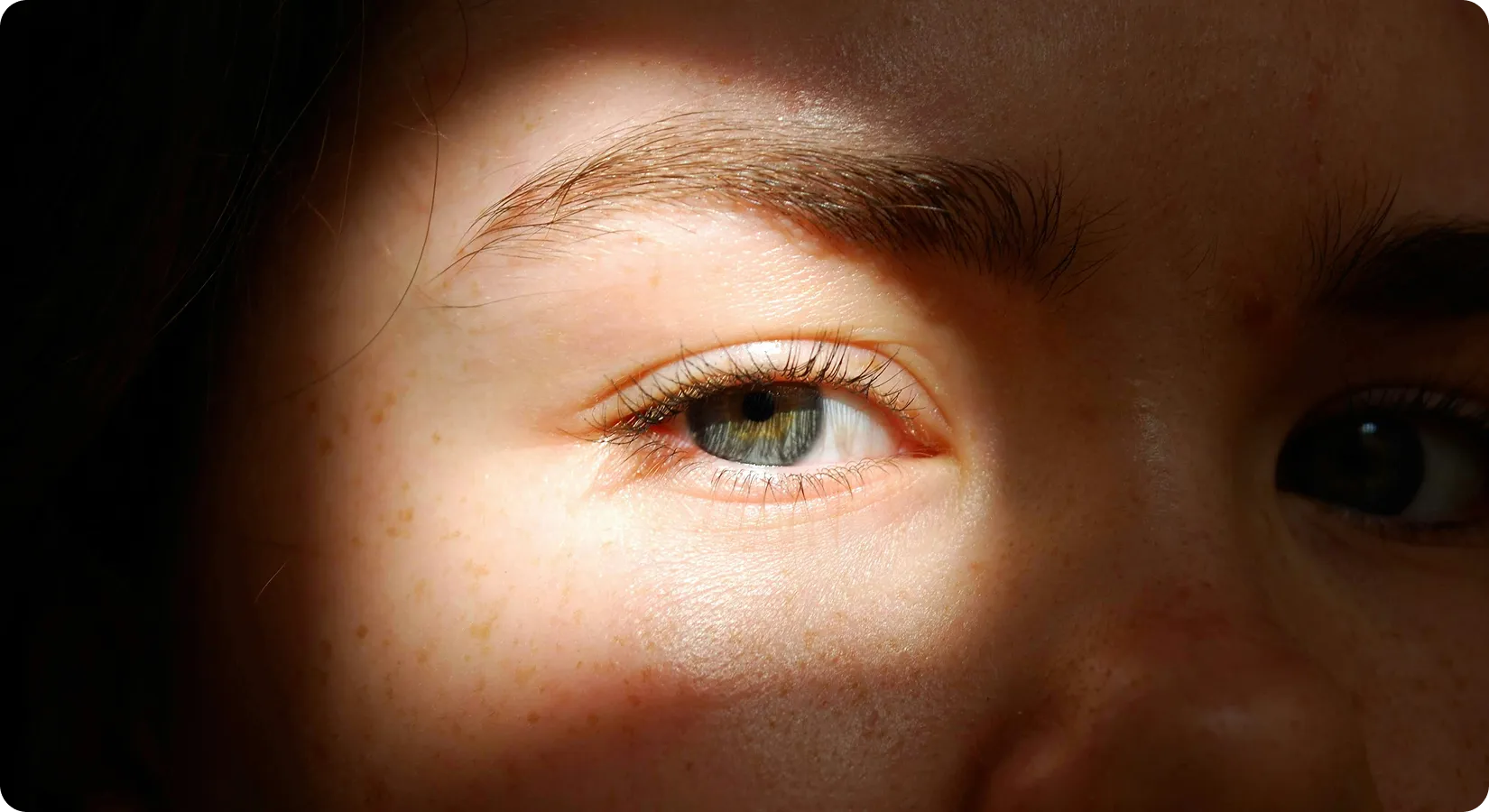Close-up of a person’s eye lit by a band of warm light